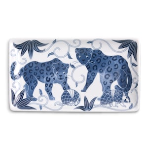 Peut inclure: Un plat de service rectangulaire en céramique avec un motif bleu et blanc. Le plat représente deux léopards et deux tatous dans un motif feuillu.