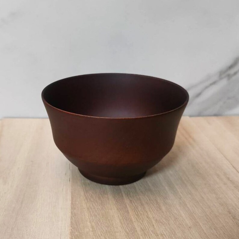 May include: A dark brown wooden bowl with a rounded shape and a slightly flared rim.