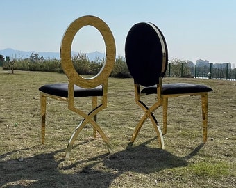 May include: Two gold metal chairs with black velvet seats. The chairs have a circular back with a gold metal frame.