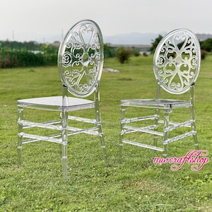 以下が含まれることがあります： 装飾的な背もたれが付いた透明なプラスチック製の椅子が2脚。椅子はシンプルでミニマルなデザインで、透明な仕上げになっています。