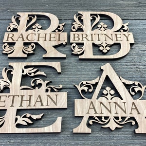 May include: Four wooden letters with decorative flourishes and names engraved on a horizontal bar. The letters are R, B, E, and A. The names are Rachel, Britney, Ethan, and Anna.