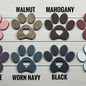 May include: Eight wooden paw prints with a heart cutout in the center, painted in various colors: pink, walnut, mahogany, red, purple, worn navy, black, and white.
