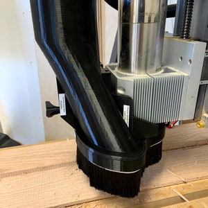 May include: A black 3D printed dust collection system with a brush attachment for a CNC router. The system is attached to a router with a silver spindle that reads "24000 RPM".