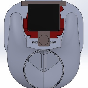 May include: A gray plastic bottle cap with a red and black top. The cap has a small, round hole in the center and the text "TRIC 2MM" printed on the side.