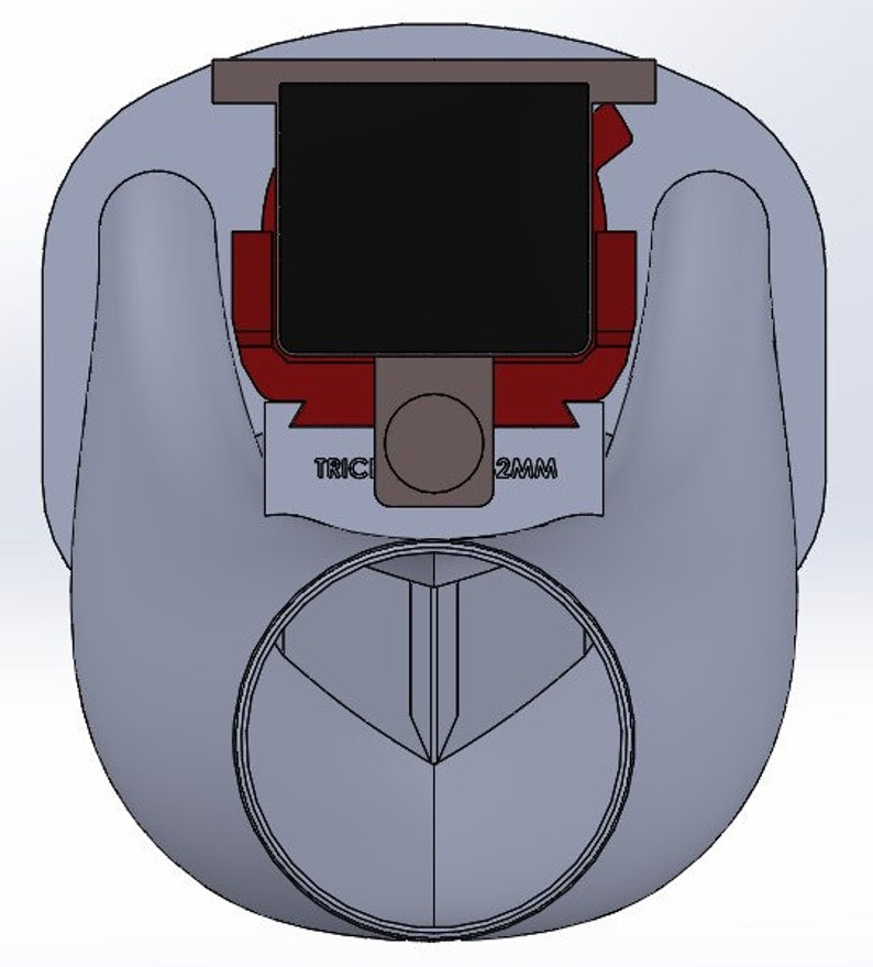 May include: A gray plastic bottle cap with a red and black top. The cap has a small, round hole in the center and the text "TRIC 2MM" printed on the side.