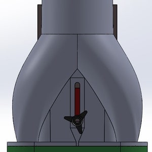 May include: A gray and black ceramic pottery wheel with a red and black indicator. The wheel has a three-pronged black knob and is mounted on a green base.