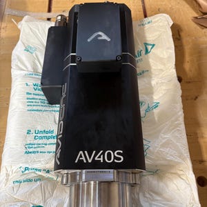 May include: A black industrial spindle motor featuring the text AV40S and AvidCNC printed on the side. The unit has a metallic silver cylindrical base and a black rectangular top housing with a white logo. A serial number is visible on the metal collar.