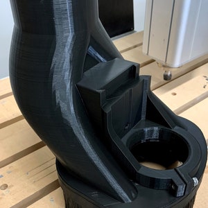 May include: A black 3D printed dust collection system with a brush attachment. The system is designed to be used with a CNC machine.