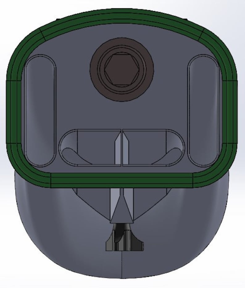 May include: A green and gray plastic object with a hexagonal hole in the center and two rectangular openings on either side. The object has a rounded top and a pointed bottom.