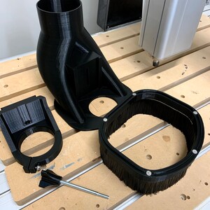 May include: A black 3D printed dust collection system for a CNC machine. The system includes a dust shroud, a dust collector, and a mounting bracket. The system is designed to help keep the work area clean and free of dust.