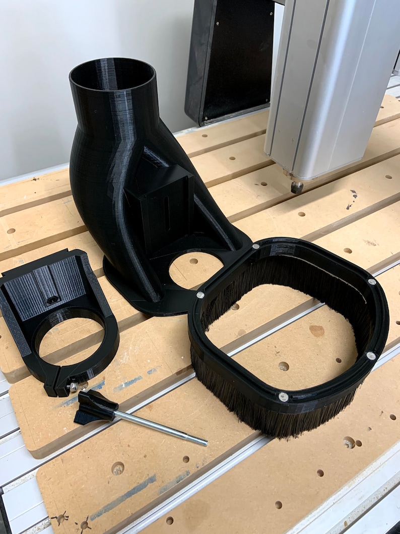 May include: A black 3D printed dust collection system for a CNC machine. The system includes a dust shroud, a dust collector, and a mounting bracket. The system is designed to help keep the work area clean and free of dust.
