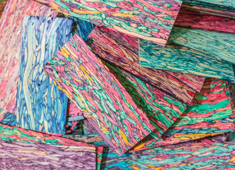 May include: A stack of colourful wooden blanks with a swirling pattern of pink, blue, green, and yellow. The wood is cut into rectangular shapes and is ready for crafting.