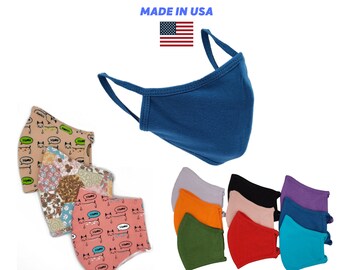 Può includere: Una varietà di maschere per il viso, tra cui colori solidi come blu, viola, arancione, verde e rosso, nonché maschere con motivi con un design a gatto. Le maschere sono realizzate negli Stati Uniti.  MADE IN USA è scritto in blu sopra una piccola bandiera americana.