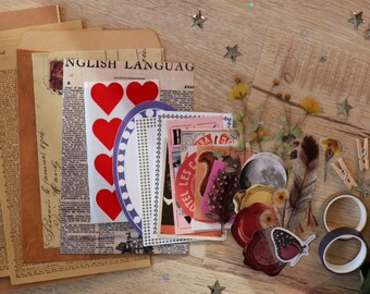May include: A collection of vintage-style scrapbook supplies, including paper ephemera, stickers with red hearts, decorative tape, and small wooden clothespins. The items are arranged on a wooden surface with scattered star-shaped confetti and dried flowers.