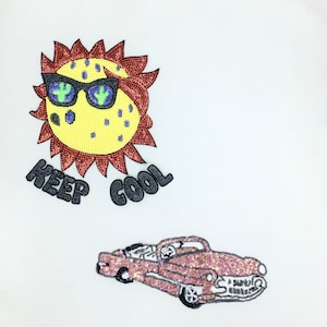 May include: A set of two iron-on patches. One patch features a cartoon sun wearing sunglasses with the text "KEEP COOL" below. The other patch features a pink car with a black outline.