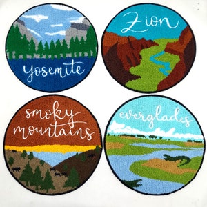 Puede incluir: Cuatro parches bordados con diferentes escenas de parques nacionales. Los parches son circulares y presentan los nombres "Yosemite", "Zion", "Smoky Mountains" y "Everglades" en letras cursivas blancas.