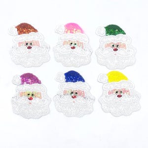 May include: Six Santa Claus face iron-on patches with sequin details. The patches are in various colours including pink, blue, green, yellow, orange, and purple.