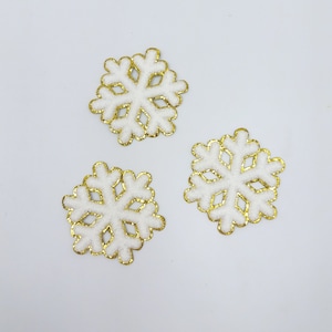 May include: Three white snowflake ornaments with gold glitter trim. The snowflakes are on a white background.