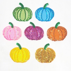 Op de afbeelding: Zes kleurrijke, van pailletten gemaakte patches in de vorm van pompoenen. De pompoenen zijn groen, blauw, roze, paars, oranje en geel.