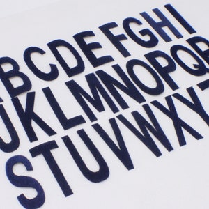 May include: A set of 26 navy blue felt letters, each letter of the alphabet is individually cut out and arranged in alphabetical order.