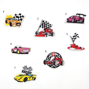 May include: Seven iron-on patches featuring different race car designs. The patches are numbered 1 through 7. The patches feature red, yellow, pink, and orange race cars with checkered flags.