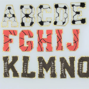 Peut inclure: Un ensemble de lettres en feutre sur le thème du sport. Les lettres A à E sont blanches avec des motifs de ballon de football noirs. Les lettres F à J sont rouges avec des motifs de ballon de basket noirs. Les lettres K à O sont brunes avec des motifs de ballon de rugby blancs.