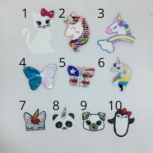 May include: A collection of sequined patches featuring various designs. Includes a white cat with a pink bow, a unicorn, a butterfly, a panda, a dog, and a penguin. The patches are in various colors, including white, pink, blue, and red.