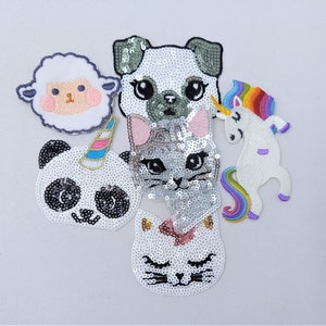May include: A set of five iron-on patches featuring various animals. The patches are made of white fabric with sequins and embroidered details. The animals include a panda, a cat, a dog, a unicorn, and a sheep.