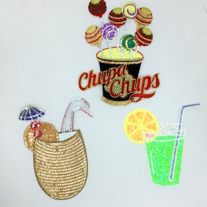 May include: Three embroidered iron-on patches featuring summer-themed designs. The first patch is a cup of lollipops with the text "Chupa Chups". The second patch is a cocktail in a coconut with a straw and an umbrella. The third patch is a glass of lemonade with a lemon slice and a straw.