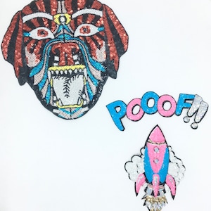 May include: Three iron-on patches with a colourful, sequined design. The first patch is a tiger face with orange, black, blue, and white sequins. The second patch is the word "POOOOF!" in blue and pink sequins. The third patch is a pink and blue rocket with a cloud of white sequins.