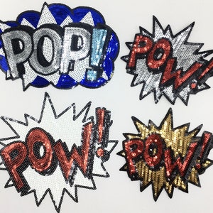 Può includere: Quattro toppe da stirare a tema fumetto. Le toppe sono realizzate in paillettes e presentano le parole "POP!" in blu e argento, "POW!" in rosso e argento, "POW!" in rosso e oro e "POW!" in rosso e bianco.