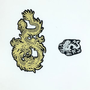 May include: Two embroidered iron-on patches featuring a gold dragon design. The larger patch is a detailed design of a dragon curled in a circle. The smaller patch is a simple design of a dragon in a curled position.