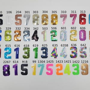 May include: A collection of colourful, sequined iron-on patches in the shape of numbers. The numbers range from 0 to 9 and are arranged in rows. The patches are perfect for adding a unique touch to clothing, bags, and other accessories.
