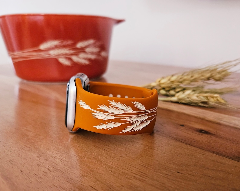 K&ouml;nnte beinhalten: Orangefarbenes Silikonarmband f&uuml;r Apple Watch mit einem wei&szlig;en Weizenmuster.