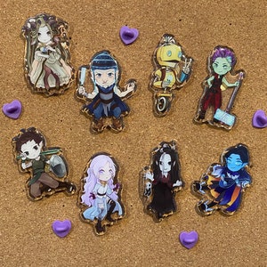 May include: Eight colorful character pins on a corkboard background. The pins are made of clear acrylic and feature various characters with different expressions and poses.