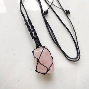 May include: A pink rose quartz crystal pendant necklace with a black macrame cord and black beads.