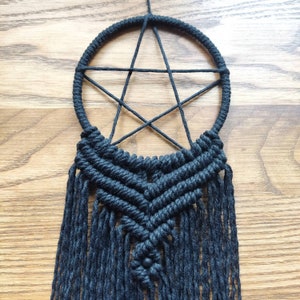 Op de afbeelding: Zwarte macram&eacute; droomvanger met een stervormig ontwerp en zwarte kralen.