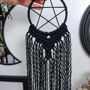 Op de afbeelding: Zwarte macram&eacute; droomvanger met een pentagram-ontwerp en lange franjes.