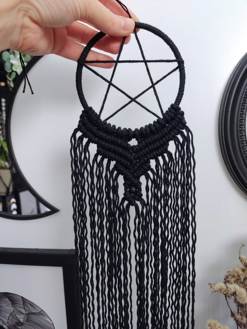 Op de afbeelding: Zwarte macram&eacute; droomvanger met een pentagram-ontwerp en lange franjes.