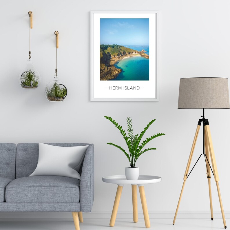 Puede incluir: Una fotograf&iacute;a enmarcada de un paisaje costero con una bah&iacute;a azul turquesa y una costa rocosa. El texto "Herm Island" est&aacute; impreso debajo de la imagen.