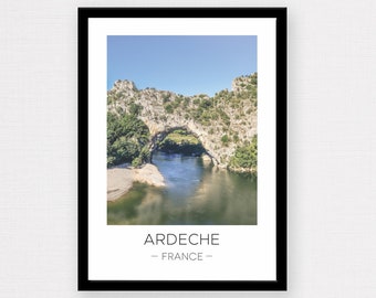 May include: A scenic photograph of a natural stone archway over a river in the Ardeche region of France. The archway is covered in green trees and the river is a light blue color.
