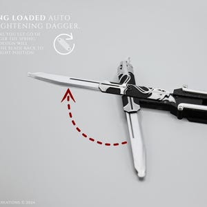 K&ouml;nnte beinhalten: Ein schwarzes und silbernes automatisch sich richtendes Springmesser mit einer silbernen Klinge und einem schwarzen Griff. Die Klinge ist gebogen und der Text "SPRING LOADED AUTO STRAIGHTENING DAGGER" ist auf dem Bild zu sehen. Der Text "AS SOON AS YOU LET GO OF THE DAGGER THE SPRING LOADED DESIGN WILL RETURN THE BLADE BACK TO THE STRAIGHT POSITION" ist ebenfalls auf dem Bild zu sehen.