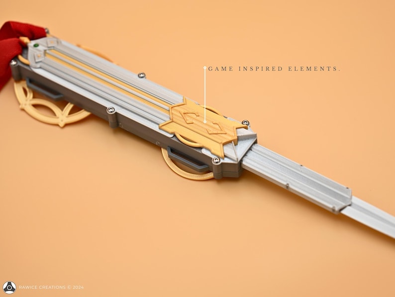May include: A silver and gold-colored prop weapon with a blade and a decorative handle. The handle features a gold design with a geometric pattern. The text "GAME INSPIRED ELEMENTS." is visible in the image.