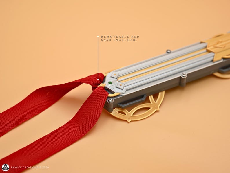 May include: A gold and silver decorative sword with a red sash. The sword has a detailed design and is attached to a red ribbon.