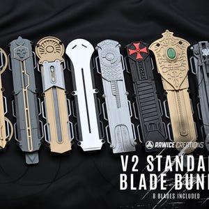 Peut inclure: Ensemble de huit lames V2 Standard de différentes couleurs, dont or, gris et noir. Chaque lame présente des motifs complexes. Le texte "V2 STANDARD BLADE BUNDLE" et "8 BLADES INCLUDED" est visible.