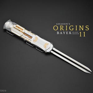 May include: A silver and white Assassin's Origins Bayek Blade Design 11 blade with two sharp edges. The blade has gold accents and is set against a black background. The text "ASSASSIN'S ORIGINS BAYEK BLADE DESIGN 11" is in gold.