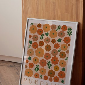 May include: A white framed print featuring a pattern of orange and brown pumpkins and green leaves on a light peach background. The text "PUMPKINS" is at the bottom of the print.