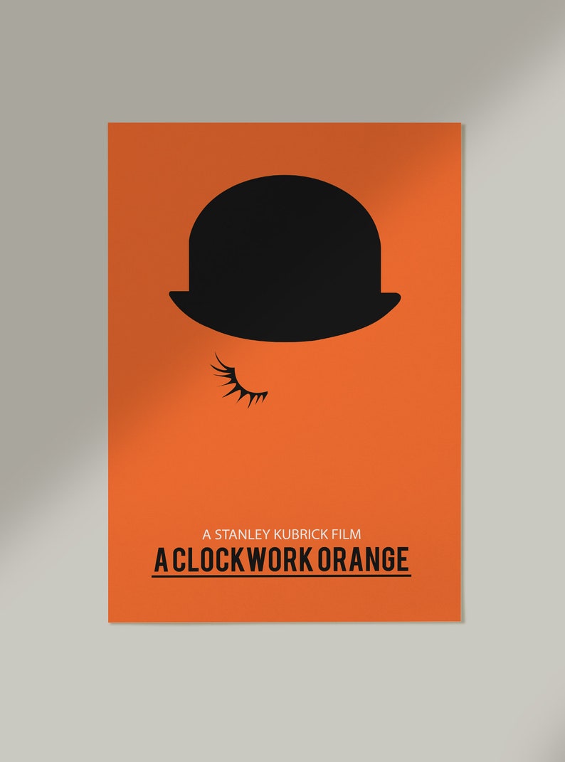 Puede incluir: Un p&oacute;ster minimalista con un fondo naranja que presenta un sombrero bomb&iacute;n negro y una sola pesta&ntilde;a. El texto "A Stanley Kubrick Film A Clockwork Orange" est&aacute; impreso en negro en la parte inferior del p&oacute;ster.