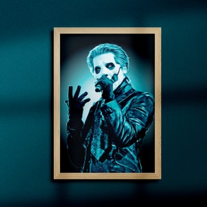 Può includere: Un ritratto incorniciato di un musicista che indossa una giacca di pelle nera e una maschera di teschio bianca. Il musicista canta in un microfono e ha uno sfondo blu e bianco.