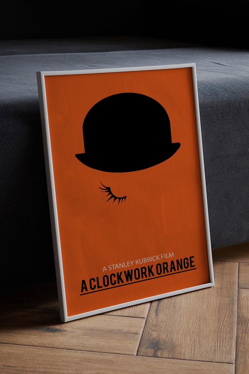 Puede incluir: Un p&oacute;ster enmarcado con fondo naranja y una silueta negra de un bomb&iacute;n con una pesta&ntilde;a. El texto "A STANLEY KUBRICK FILM A CLOCKWORK ORANGE" est&aacute; impreso en negro en la parte inferior del p&oacute;ster.